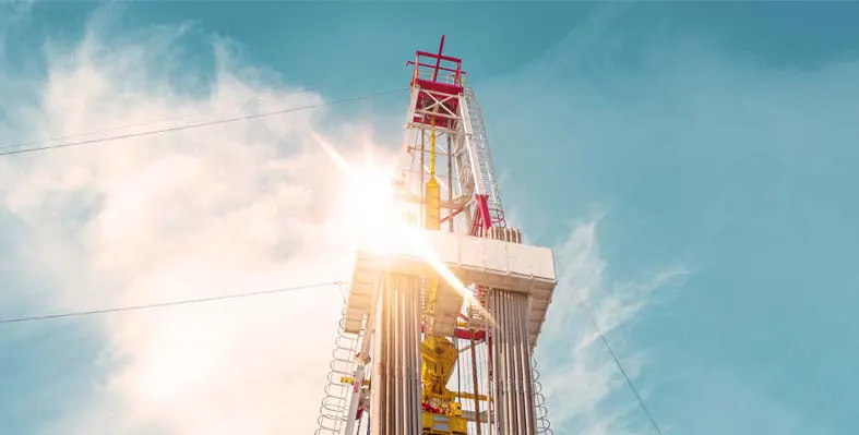 Top half of an oil rig with blue sky and cloud